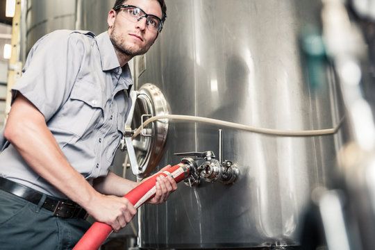 Close-up of employee hooking up hose to huge steel tank. Red Lodge, Montana, USA