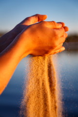 Sand, der am Strand im warmen Abendlicht durch die Hände rinnt