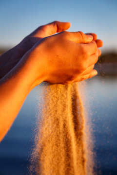 Sand, der am Strand im warmen Abendlicht durch die H&auml;nde rinnt