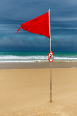 Rote Flagge am Strand in Lacanau Océan, Frankreich, bei aufziehenden, dunklen Gewitterwolken