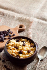 Sweet millet porridge with dark raisins in ceramic rustic bowl
