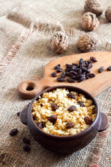 Sweet millet porridge with dark raisins in ceramic rustic bowl