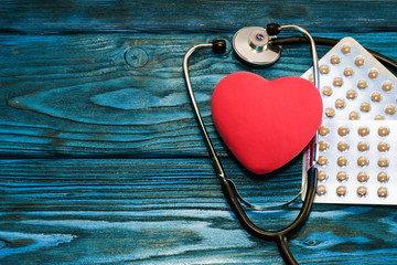 A heart with a stethoscope lies on a wooden background. Healthy heart