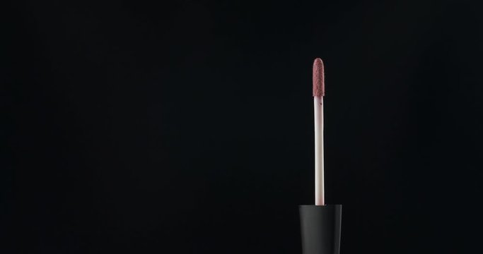 Rotation, lip gloss brushes on a black background.