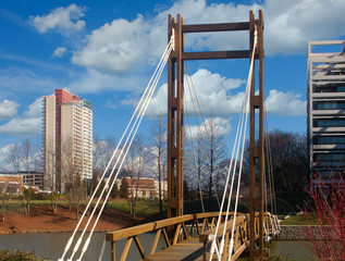 A wood suspension bridge over a lake in an office park
