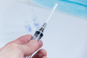 syringe with needle covered in mans hand close up image.