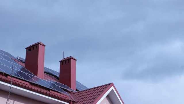 Solar PV modules mounted on rooftop of a house against the background of the sky and clouds, time lapse
