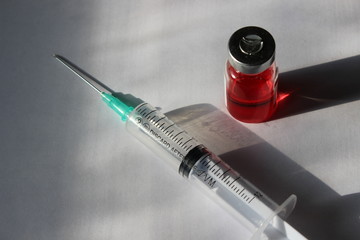 bottle of vaccine and a syringe on a white background
