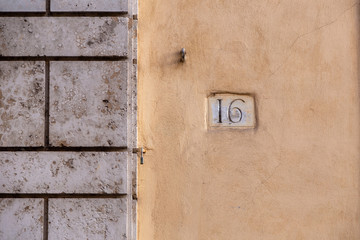 Obraz premium number 16, ancient house number plate on brick wall, Italy