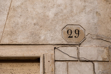 number 29, ancient house number plate on brick wall, Italy