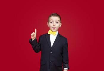 Cute boy in suit pointing up