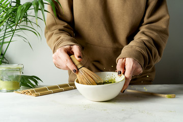 Making Japanese  matcha latte, tea is whipped with a bamboo whisk, traditional matcha tools on white background.