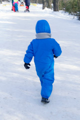 Fototapeta na wymiar child runs on a snowy track in a park