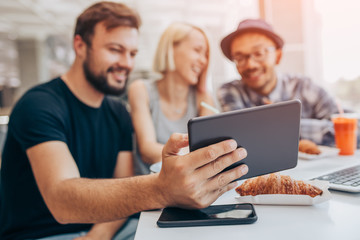 Man sitting with friends and using tablet in cafe