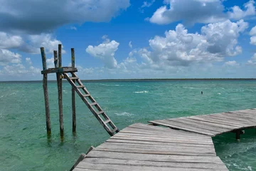 Fotobehang een houten wegplatform op een turquoise water- en natuurparadijsachtergrond © Cruzcaba