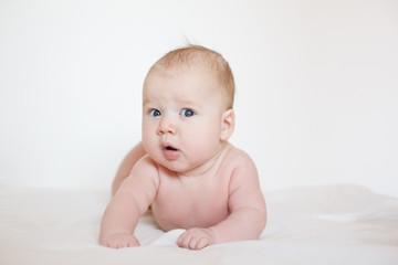 the naked baby lies on his stomach and looks in surprise. on a white background. selective focus