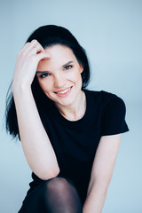 Young adult woman posing on neutral backdrop. Casual outfit.