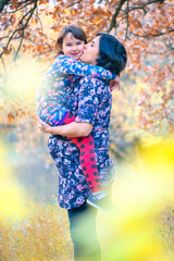 Happy family. Pregnant mom and little daughter hugging and kissing at sunset in autumn in forest. Laughter, happiness and fun together