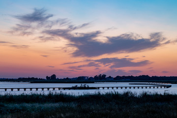 sunset over the lake with a wooden bridge.