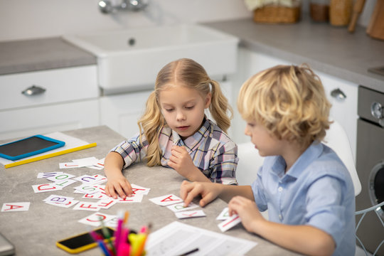 Two Blond Kids Learning Letters And Looking Interested