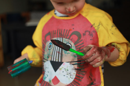 Close up child's hands paint with rollers and sponges and a palette