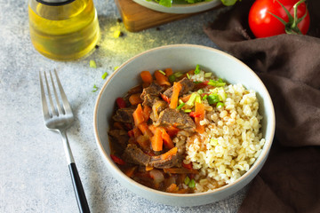 Healthy eating concept. Beef stewed with vegetables in bulgur sauce and fresh vegetable salad on a light stone table top.