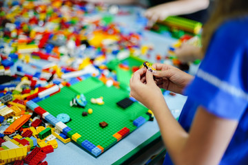 Little kid playing with lots of colorful plastic blocks indoor. Children playing toys inside school.