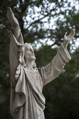 A statue of Jesus Christ with his hands raised up looking at the sky