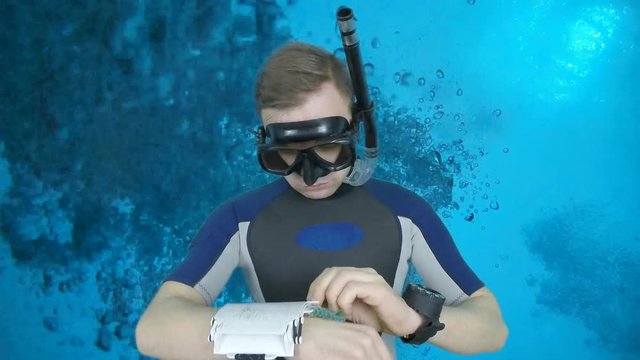 Divemaster writing underwater on the plate and shows signal ok