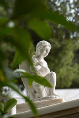 An Angel standing at one knee in prayer pose with green at the front and sides