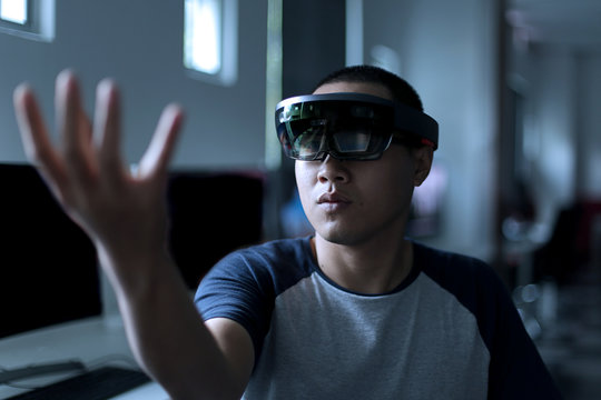 Young asian student trying Mixed reality with VR glasses in the laboratory. Gesture of men when using Virtual Reality headset.