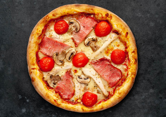  meat pizza with cheese, chicken, ham, mushrooms, tomatoes on a stone background