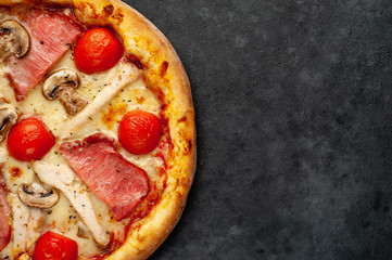 meat pizza with cheese, chicken, ham, mushrooms, tomatoes on a stone background with copy space for your text