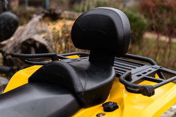 bottom view of modern yellow all-terrain vehicle standing on cloudy day. Quad bike in dust cloud, sand quarry on background. Racing in the sand on a four-wheel drive quad.