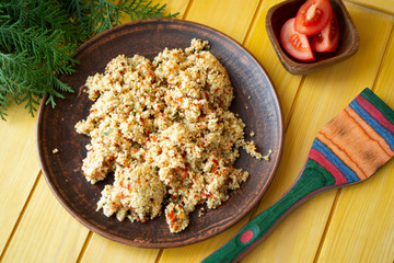 Light healthy dietary vegan dish, couscous and colorful vegetables on a yellow wooden background. The top view.