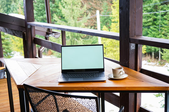 Morning coffee and laptop on a wooden table on the terrace, outdoors.