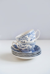 Ceramic saucers with a cup for tea in blue with flowers. New luxury elegance dinnerware on a isolated white background. Trendy plate. Flat lay view.