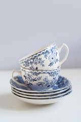 Ceramic saucers with a cup for tea in blue with flowers. New luxury elegance dinnerware on a isolated white background. Trendy plate. Flat lay view.