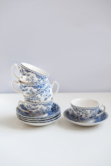 Ceramic saucers with a cup for tea in blue with flowers. New luxury elegance dinnerware on a isolated white background. Trendy plate. Flat lay view.