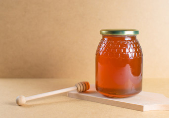 Jar of natural honey on wooden board with spoon for honey on wooden background