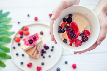Slice of classic cheesecake with fresh berries on the white plate - healthy organic summer dessert.