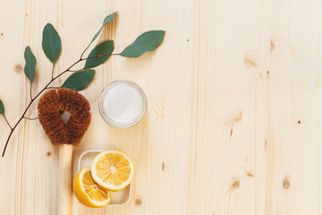 eco friendly house cleaners, baking soda, lemon, bamboo cleaning brush and blue cloth on wooden...