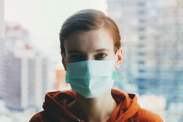 close up young woman wearing surgical mask because of viruses and air pollution in the city
