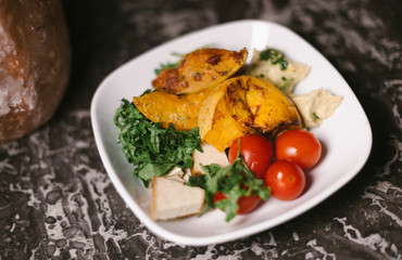 Vegetarian lunch meal pumpkin, tomatoes with tofu and greens in a white plate