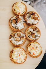 Tasty snacks in baskets. Cold appetizers with fish in baskets and a salad with crab sticks