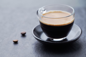 Coffee in glass cup on dark stone background. Close up.