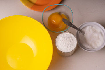 Ingredients for homemade pie stand on the table. Flour, sugar and egg. Close-up.