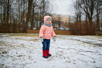 Adorable little toddler girl in park on a spring or winter day