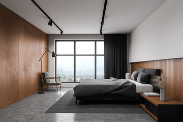 White and wooden bedroom with armchair and window