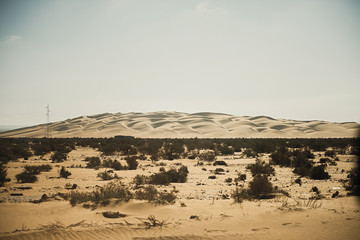 Silhouette of power line by desert landscape on a hazy day